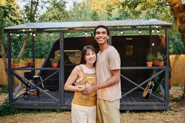 Ein gemischtrassiges Paar hält ein Glas Wein in der Hand und genießt einen romantischen Moment in seinem Wohnmobil während eines Kurzurlaubs. — Stockfoto