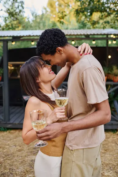 Ein Mann und eine Frau, ein gemischtes Paar, stehen nebeneinander und halten Weingläser in der Hand und genießen einen romantischen Moment zusammen. — Stockfoto