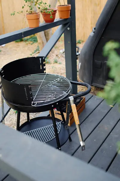 Una acogedora escena de barbacoa en una cubierta de madera rodeada de exuberantes plantas en maceta, creando una experiencia de comedor al aire libre serena. - foto de stock