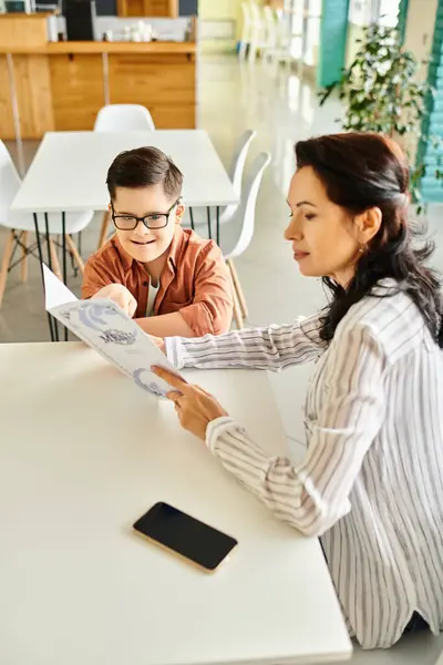 Beautiful mother in casual attire looking at menu in cafe with her inclusive son with Down syndrome — Stock Photo