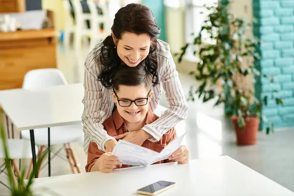 Joyful good looking mother in casual clothes with her inclusive son with Down syndrome holding menu — Stock Photo
