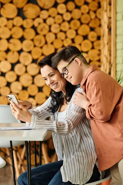 Joyful mother in cozy clothes with her son with Down syndrome looking at menu on smartphone — Stock Photo