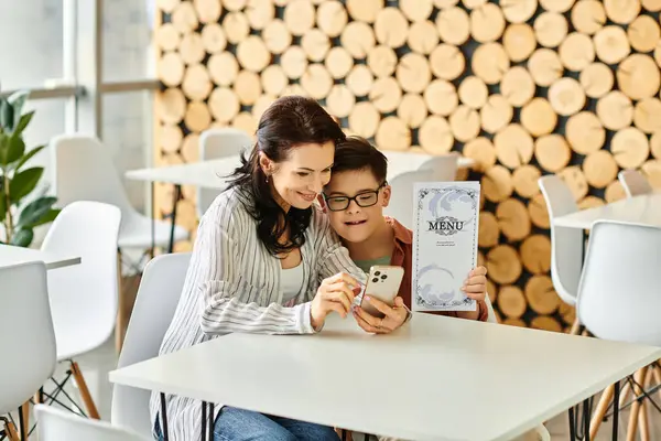 Fröhliche Frau in kuscheliger Kleidung mit ihrem Sohn mit Down-Syndrom beim Blick auf Speisekarte auf dem Smartphone — Stockfoto