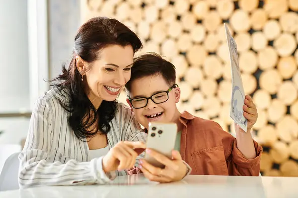 Mulher alegre em roupas acolhedoras com seu filho com síndrome de Down olhando para o menu no smartphone — Fotografia de Stock