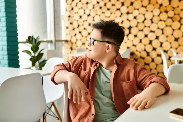 Joyous preadolescent inclusive boy with Down syndrome in casual attire looking away while in cafe — Stock Photo