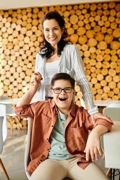 Mãe alegre atraente olhando para a câmera enquanto passa o tempo com seu filho com síndrome de Down — Fotografia de Stock