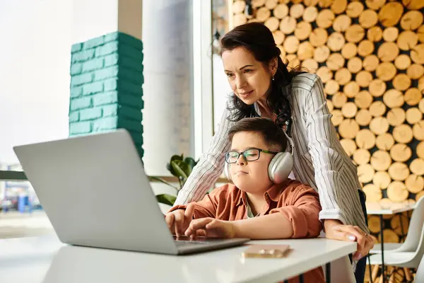 Fröhliche Mutter verbringt Zeit mit ihrem Sohn mit Down-Syndrom im Café, während er am Laptop spielt — Stockfoto