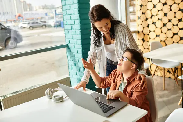 Adorable inclusive boy with Down syndrome spending time with his joyful mother in front of laptop — Stock Photo