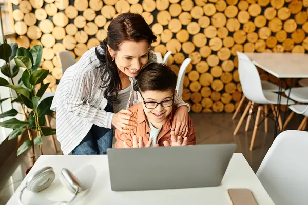 Bela mãe alegre olhando para laptop com seu filho bonito inclusivo com síndrome de Down no café — Fotografia de Stock