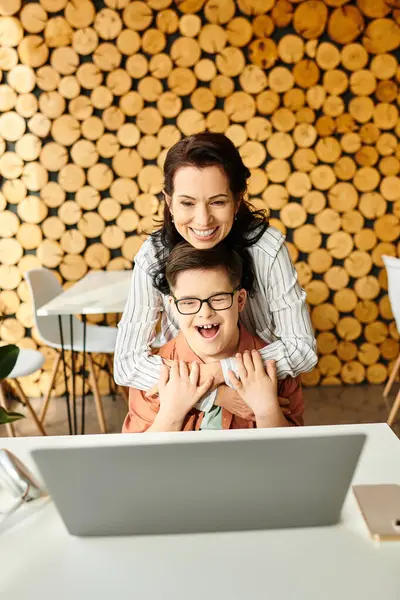 Bella madre gioiosa guardando il computer portatile con il suo figlio carino inclusivo con la sindrome di Down in caffè — Foto stock