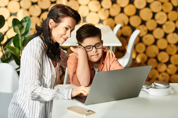 Entzückender inklusiver Junge mit Down-Syndrom, der Zeit mit seiner fröhlichen Mutter vor dem Laptop verbringt — Stockfoto