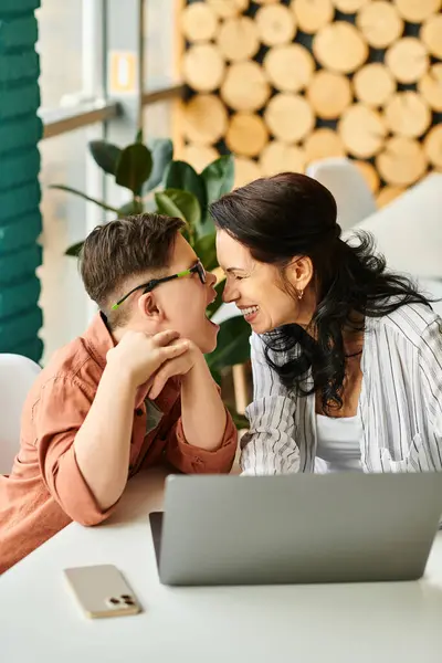 Amorosa madre alegre teniendo tiempo de calidad con su hijo alegre inclusivo con síndrome de Down en la cafetería - foto de stock