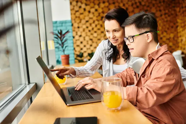 Joyful inclusive boy with Down syndrome with headphones playing on laptop near his mother in cafe — Stock Photo