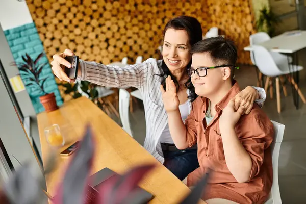 Beautiful jolly mother taking selfie with her preteen inclusive son with Down syndrome in cafe — Stock Photo