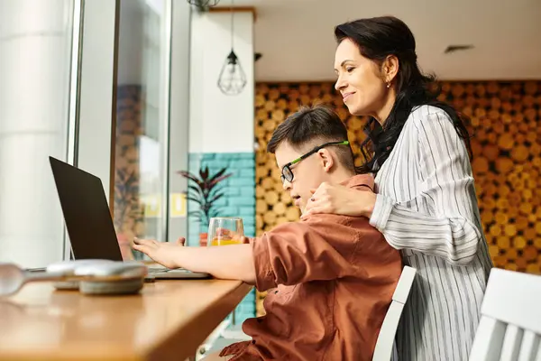 Joyous mother spending time with her inclusive son with Down syndrome in front of laptop in cafe — Stock Photo