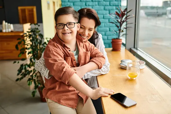 Joyous mother spending quality time with her cheerful son with Down syndrome with smartphone — Stock Photo