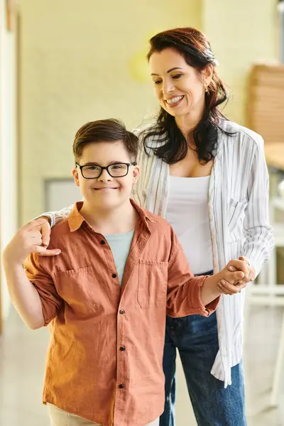 Felice ragazzo preadolescente inclusivo con la sindrome di Down in posa con la sua allegra madre e sorridente alla fotocamera — Foto stock