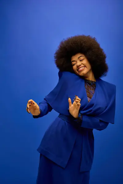 Stylish African American woman with curly hairdostrikes a pose on vibrant backdrop. — Stock Photo