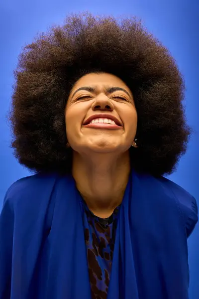 Stylish African American woman with curly hairdosmiling in a trendy blue jacket. — Stock Photo