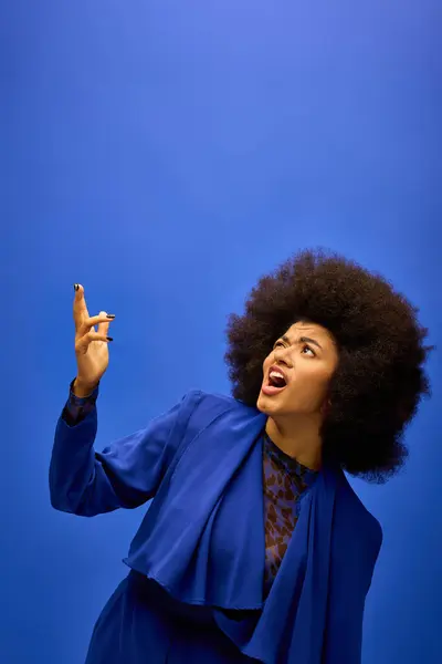 Stylish African American woman with curly hairdomakes a funny face on vibrant backdrop. — Stock Photo