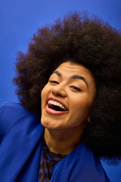 Trendy African American woman with curly hairdolaughing in stylish blue jacket. — Stock Photo