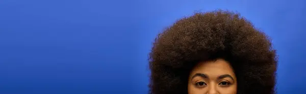 Mulher afro-americana elegante em trajes da moda fazendo um rosto engraçado com seu cabelo afro. — Fotografia de Stock