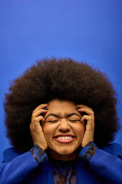 Une femme afro-américaine élégante avec des cheveux bouclés lui tenant les mains sur le visage dans un moment de réflexion. — Photo de stock