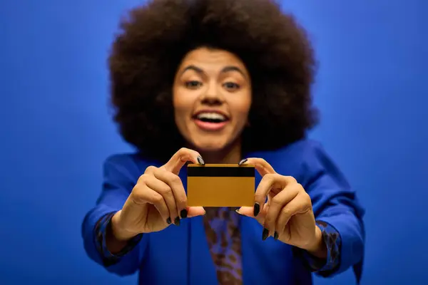 Stylish African American woman with credit card against vibrant backdrop. — Stock Photo