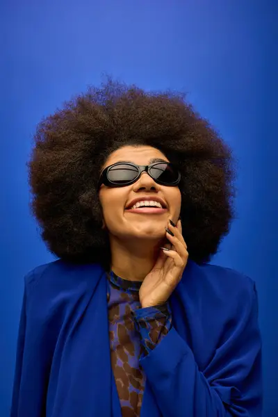 Trendy African American woman poses in blue jacket and sunglasses. — Stock Photo