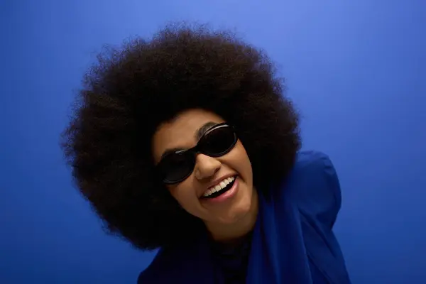 A stylish African American woman poses in trendy attire against a vibrant backdrop. — Stock Photo