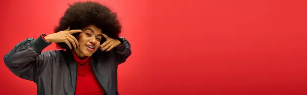 A stylish woman with curly hairdoposing actively on red backdrop. — Stock Photo