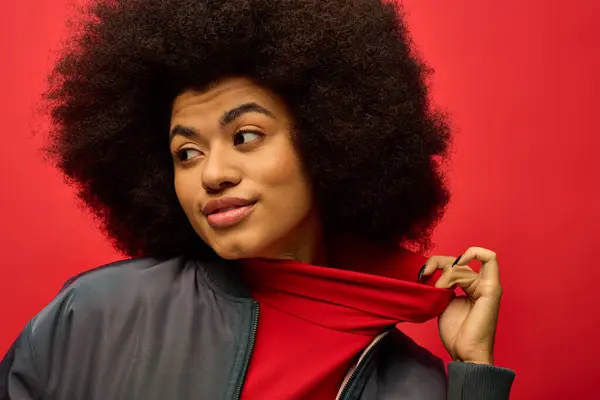 Mulher afro-americana elegante apresentando trajes da moda com um cachecol vermelho impressionante em torno de seu pescoço contra um pano de fundo vibrante. — Fotografia de Stock