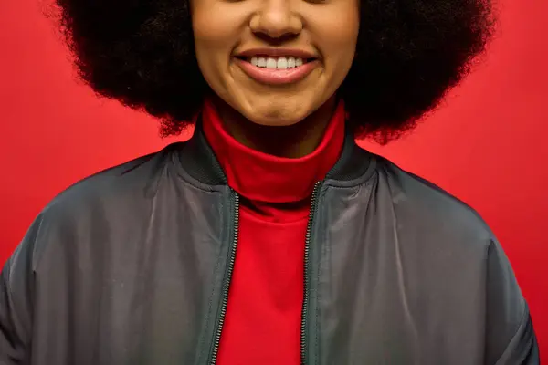 Close-up de mulher afro-americana sorrindo na jaqueta da moda contra o pano de fundo vibrante. — Fotografia de Stock