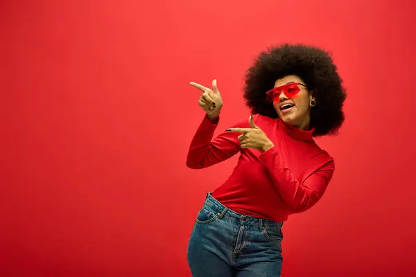 Femme afro-américaine élégante frappant une pose dans une chemise rouge à la mode et des lunettes de soleil. — Photo de stock
