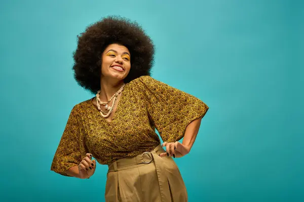 Stylish African American woman with curly hairdoposes against vibrant blue backdrop. — Stock Photo