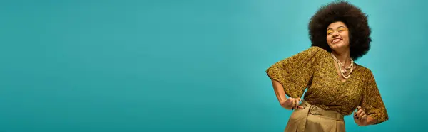 Stylish African American woman with curly hairdo posing in trendy attire against vibrant blue backdrop. — Stock Photo