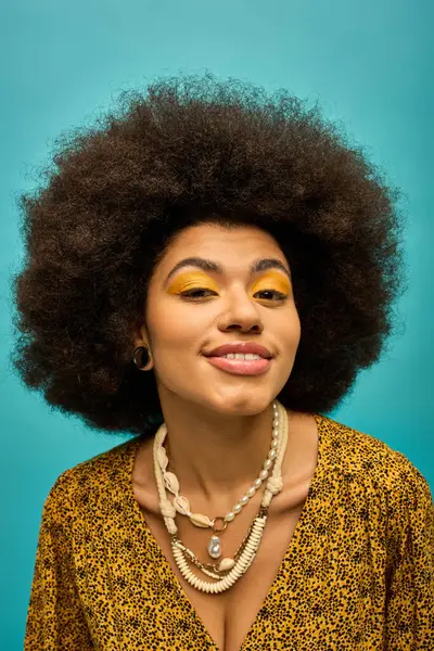 Eine afroamerikanische Frau mit auffallend afro-gelbem Make-up posiert stilvoll vor einer lebendigen Kulisse. — Stockfoto