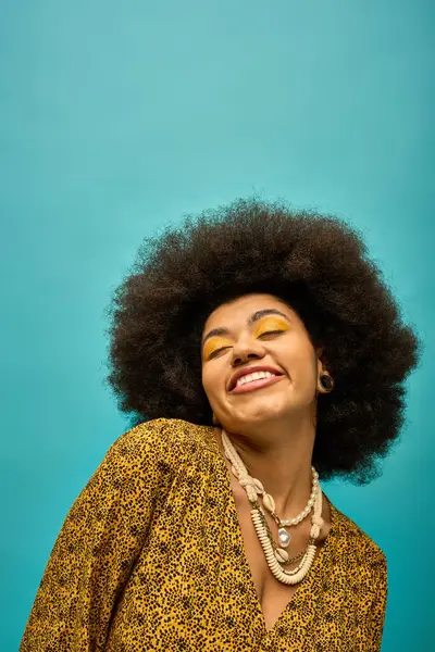 A stylish African American woman with curly hairdois smiling on a vibrant backdrop. — Stock Photo