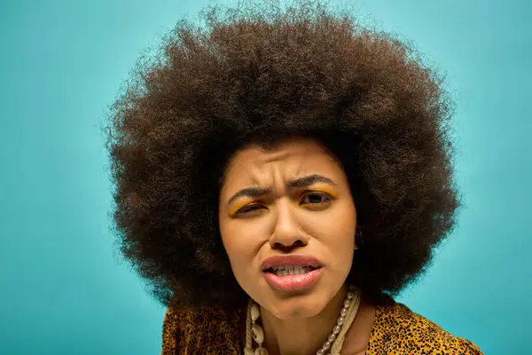 A stylish African American woman in trendy attire, with curly hairdohairstyle, looks surprised. — Stock Photo