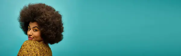 Trendy African American woman poses with curly hairdoon vibrant blue backdrop. — Stock Photo