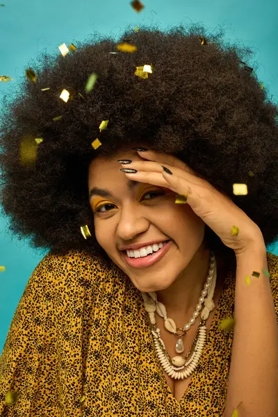 Smiling African American woman with curly hairdo surrounded by falling confetti. — Stock Photo