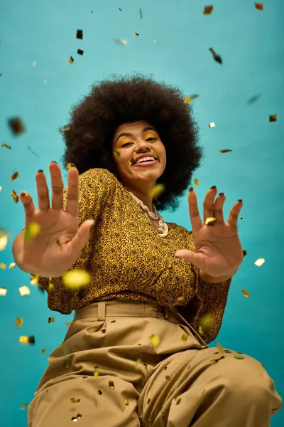 Stylish African American woman sitting on ground, hands raised in the air. — Stock Photo