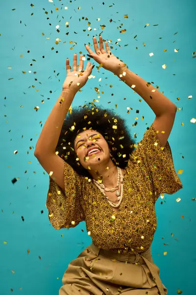 Jeune femme afro-américaine en tenue élégante lève les mains, entouré de confettis colorés. — Photo de stock