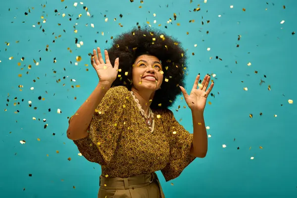 Uma mulher afro-americana elegante fica na frente de um fundo azul, alegremente cercada por confetes. — Fotografia de Stock