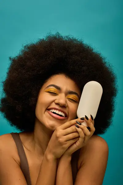 Stylish African American woman with curly hairdohair, holding a brush. — Stock Photo
