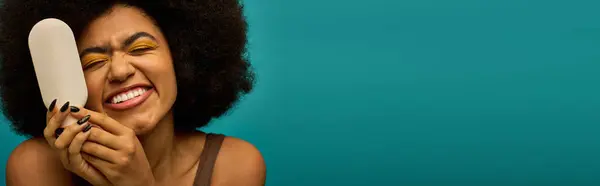 Stilvolle Afroamerikanerin mit Pinsel vor lebendigem Hintergrund. — Stockfoto