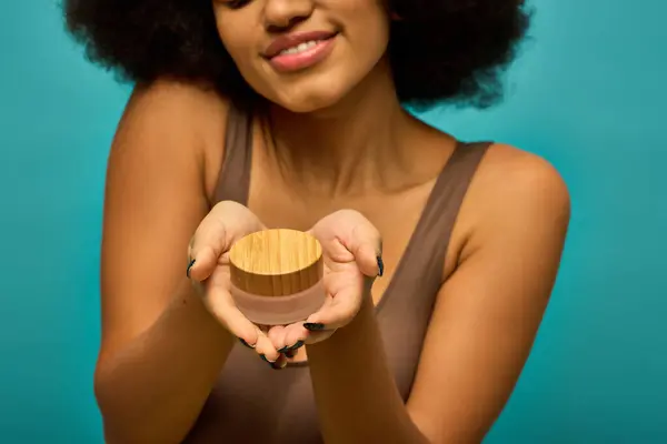 A stylish African American woman in trendy attire holding cream. — Stock Photo