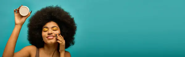 Elegante mujer afroamericana sosteniendo crema. - foto de stock