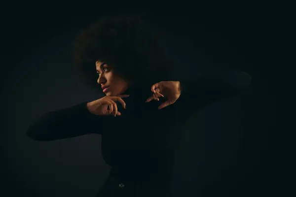A stylish African American woman with curly hairdostrikes a pose for a picture against a vibrant backdrop. — Stock Photo