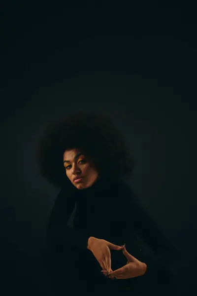 Stilvolle afroamerikanische Frau sitzt in einem dunklen Raum. — Stockfoto